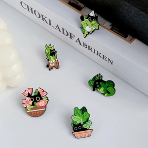 Detailed close-up of five cute black cat enamel pins with floral and leaf motifs