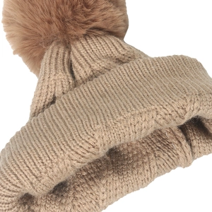 Gros plan du bonnet en tricot camel avec texture côtelée et pompon en fausse fourrure douce