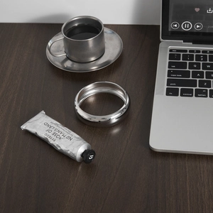 Mirror-polished wide silver stainless steel bangle displayed on a wooden desk
