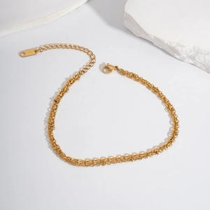 Detailed macro view of a gold double-layer stainless steel anklet with small beads