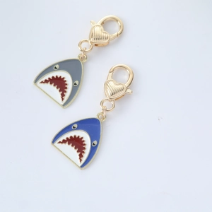 Close-up of blue and grey cartoon shark keychains with golden heart-shaped metal clasps