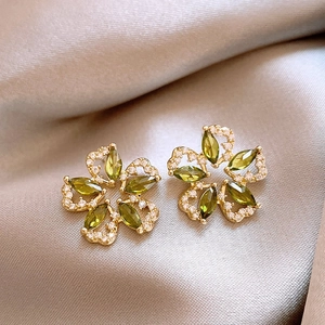 Close-up of vintage flower stud earrings with emerald green stones and clear crystals