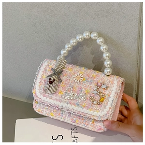 Detail of pink tweed girl's handbag with lace trim, pearls, and cute charms