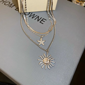 Close-up of tiered silver necklaces with starfish and vintage sun face pendants