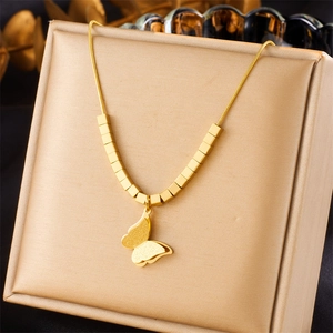 Macro detail of gold butterfly pendant with matte finish on snake chain necklace