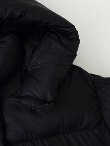 Close-up of a black padded jacket showing the high collar and smooth windproof fabric texture