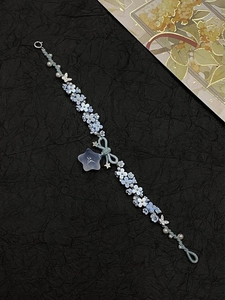Close-up of handmade blue flower bracelet with pearls, bow, and star pendant details