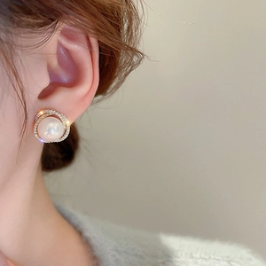 Gros plan d'une boucle d'oreille perle dorée avec halo de diamants portée par un mannequin