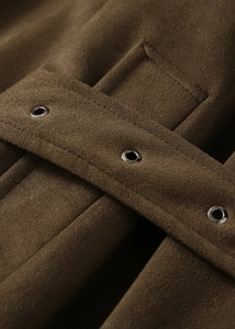 Gros plan détaillé d'un manteau en daim marron foncé avec œillets métalliques sur la ceinture