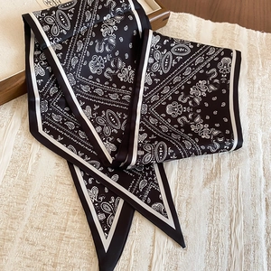 Detail of black paisley silk scarf necklace with satin texture and pointed ends