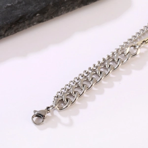 Close-up of double-layered silver alloy bracelet with Cuban link and lobster clasp detail