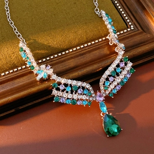 Macro shot of silver wing necklace with colorful rhinestones and teardrop green gem