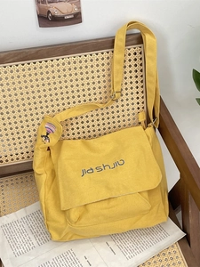Minimalist yellow canvas crossbody bag with embroidery on a vintage rattan chair