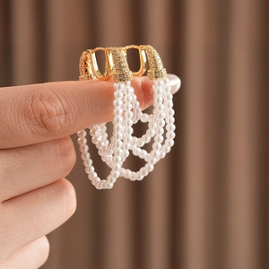 Macro view of vintage gold hoop earrings with triple rows of pearls and zircon accents