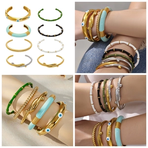 Dettaglio di bracciali sovrapposti in acciaio inossidabile con smalto colorato e malocchio