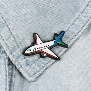 Detailed view of a 3D airplane enamel pin on denim fabric showing glossy finish