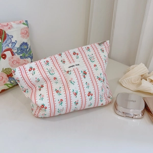Détail de la trousse à maquillage en coton à fleurs avec rayures roses et étiquette