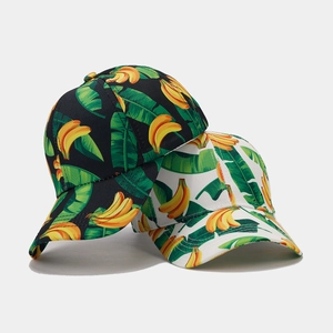 Detailed close-up of tropical banana and palm leaf print on black and white baseball caps