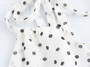 Gros plan d'une robe blanche à pois avec bords à volants étagés et tissu léger