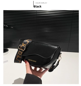 Detail of black faux leather saddle bag featuring a stylish colorful patterned strap