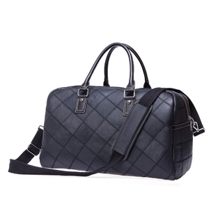 Detail of black leather travel bag featuring classic diamond quilted texture and strap