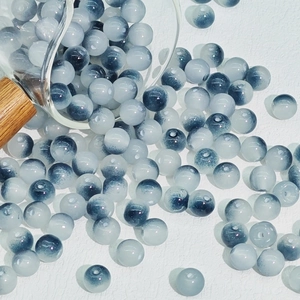 Macro shot of 8mm gradient glass beads spilling from a measuring cup for DIY jewelry