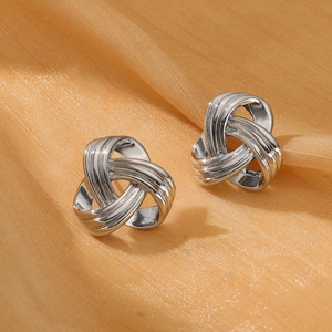 Detail view of silver knotted hoop earrings on elegant orange satin silk fabric