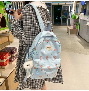 Detail of light blue strawberry backpack with cute plush charm on a real-life model
