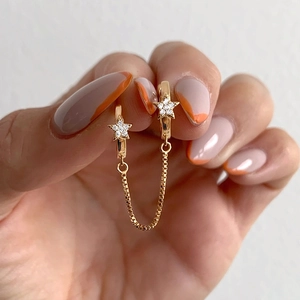 Detail of gold S925 sterling silver star earring with white zircon and chain link tassel