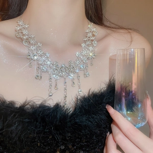 Gros plan du collier fleur argenté scintillant avec glands en strass sur modèle