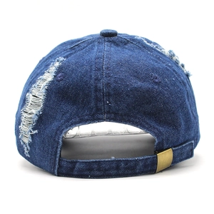 Dettaglio del cappello da baseball in denim lavato con fori consumati e fibbia in metallo