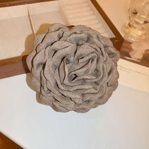 Close-up of a grey fabric rose hair claw with elegant petal texture on wooden box