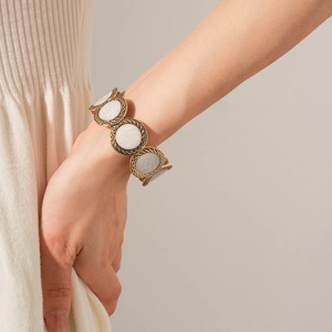 Close-up of vintage gold relief bracelet with cream enamel inlays worn by a model