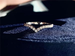 Macro shot of V-shaped sterling silver ring with pavé moissanite on blue velvet