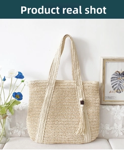 Detail of large beige woven straw tote bag with decorative tassel and wooden beads