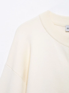 Close-up of cream knit cardigan featuring ribbed neckline and soft wool texture detail