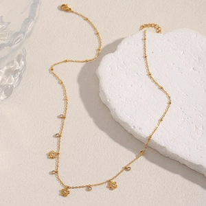 Gold plated stainless steel necklace with zircon flowers and tassels on white stone
