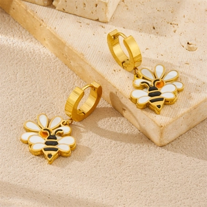 Elegant gold earrings set featuring white flower and bee charms on a stone background