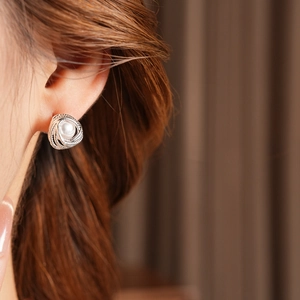 Detailed close-up of a silver twist pearl stud earring worn on a model's ear