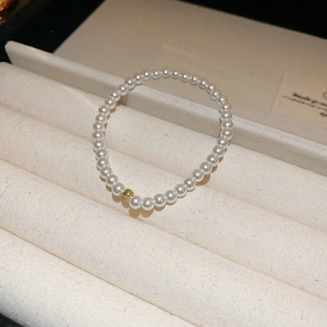 Close-up of elegant freshwater pearl bracelet with textured gold bead on jewelry tray