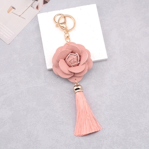 Detailed view of pink PU leather flower tassel keychain with gold ring on white block