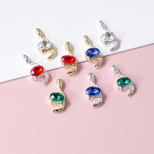 S-shaped snake nail charms with gold and silver bases featuring multi-colored gemstones