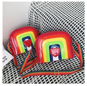Close-up of rainbow heart crossbody bag with glossy finish and wide colorful woven strap