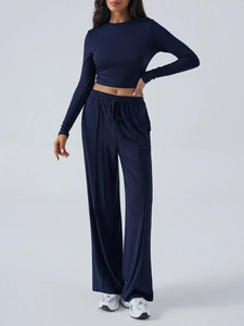 Full-body view of a dark blue yoga set featuring a long-sleeve crop top and high-waist pants
