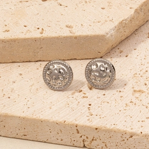 Macro view of silver geometric stud earrings with hammered texture on stone background