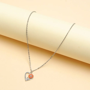 Silver heart necklace with orange enamel flower pendant on beige cylindrical display