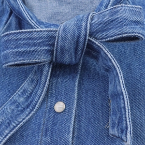 Detailaufnahme des Jeanshemd-Kragens mit Schleife und weißem Perlenknopf-Struktur