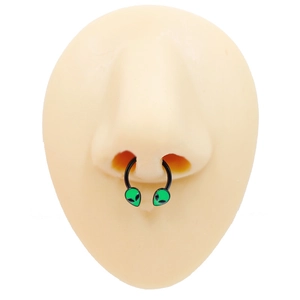 Detail of a black alien septum ring with green accents on a silicone nose model