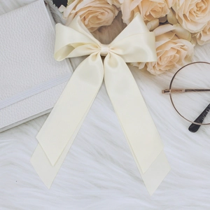Beige satin bow hair clip with streamers on soft white fur and elegant accessories