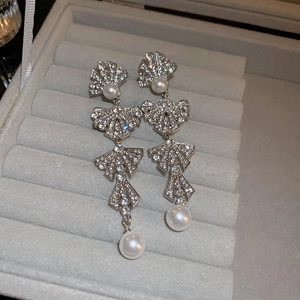 Macro view of silver fan-shaped pearl earrings with sparkling rhinestones in a gift box